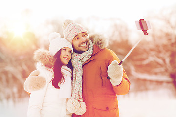 Image showing happy couple taking selfie by smartphone in winter