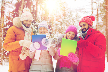 Image showing smiling friends with tablet pc in winter forest