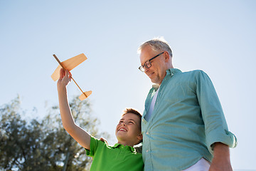 Image showing senior man and boy with toy airplane over sky