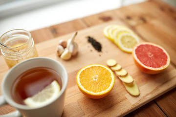 Image showing ginger tea with honey, citrus and garlic on wood