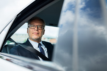 Image showing senior businessman driving on car back seat