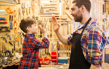 Image showing father and little son making high five at workshop