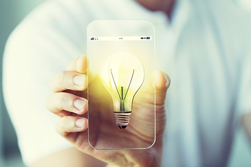 Image showing close up of hand with light bulb on smartphone