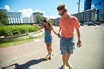 Image showing teenage couple riding skateboards on city street