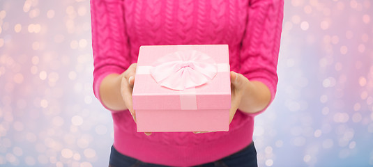 Image showing close up of woman in pink sweater holding gift box