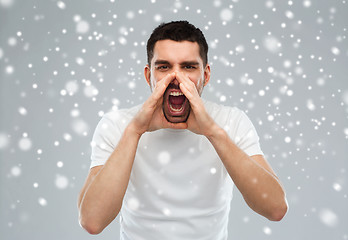 Image showing angry shouting man in t-shirt over snow background