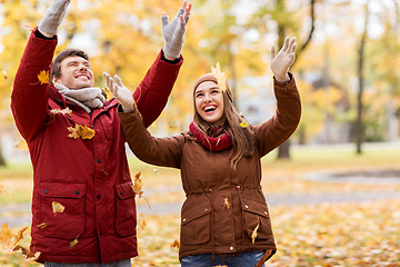 Image showing happy young couple throwing autumn leaves in park