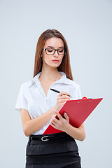 Image showing The young business woman with pen and tablet for notes on gray background