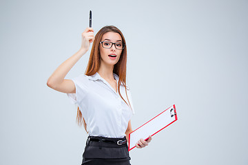 Image showing The young business woman with pen and tablet for notes on gray background