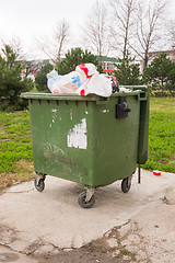 Image showing The garbage container on wheels completely packed with trash