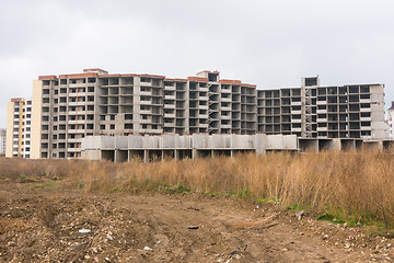 Image showing Abandoned construction of multi-storey residential complex, overgrown with weeds