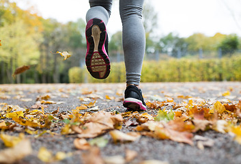 Image showing close up of young woman running in autumn park