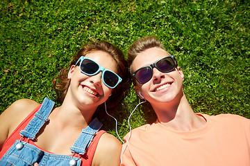 Image showing happy teenage couple with earphones lying on grass