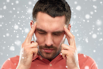 Image showing man suffering from head ache or thinking over snow