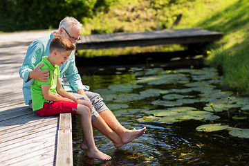 Image showing grandfather and grandson sitting on river berth