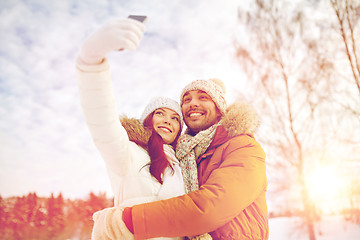 Image showing happy couple taking selfie by smartphone in winter