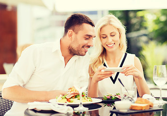 Image showing happy couple with smatphone photographing food