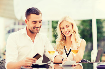 Image showing happy couple with bank card and bill at restaurant