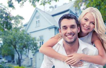 Image showing smiling couple hugging over house background