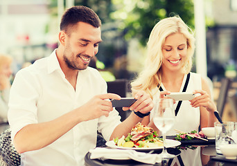 Image showing happy couple with smatphone photographing food