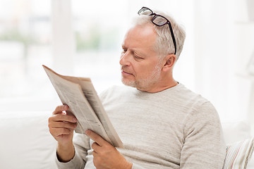 Image showing senior man in glasses reading newspaper at home