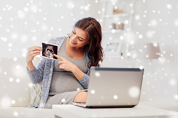 Image showing happy pregnant woman with ultrasound image at home