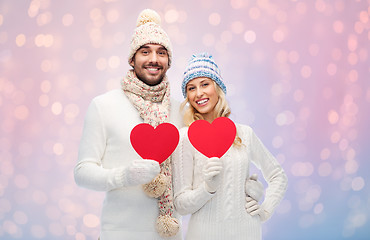 Image showing smiling couple in winter clothes with red hearts