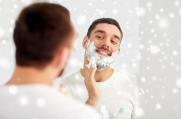 Image showing happy man applying shaving foam at bathroom mirror