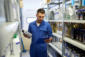 Image showing auto mechanic with oil and clipboard at car shop