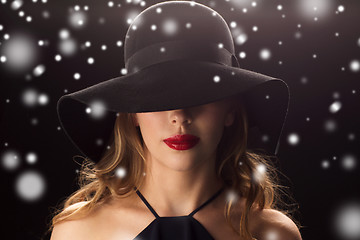 Image showing beautiful woman in black hat over snow