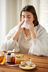 Image showing sick woman with medicine blowing nose to wipe