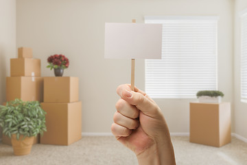 Image showing Hand Holding Blank Sign in Empty Room with Packed Moving Boxes