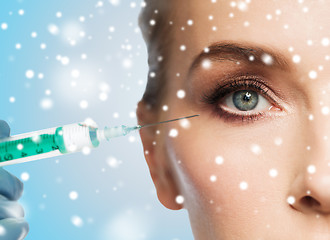 Image showing close up of woman face and syringe over snow