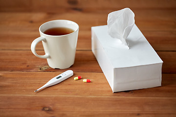 Image showing cup of tea, paper wipes and thermometer with pills