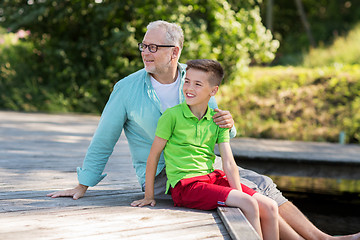 Image showing grandfather and grandson sitting on river berth