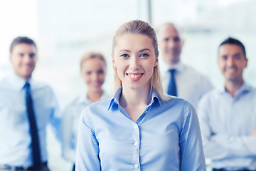 Image showing smiling businesswoman with colleagues in office