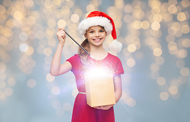 Image showing girl in santa hat with gift box and magic wand