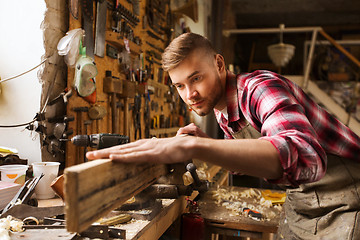 Image showing carpenter working with wood plank at workshop