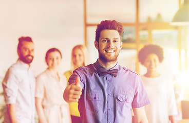 Image showing happy man showing thumbs up over team in office