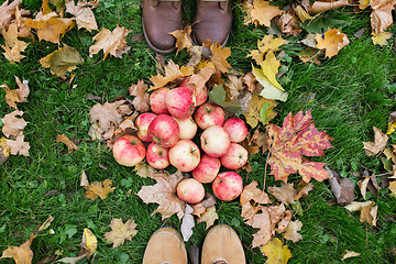 Image showing feet in boots with apples and autumn leaves