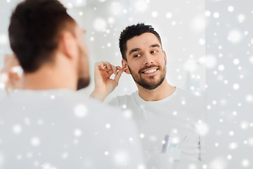 Image showing man cleaning ear with cotton swab at bathroom