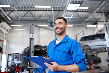 Image showing happy mechanic man with clipboard at car workshop