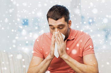 Image showing sick man blowing nose to paper napkin at home