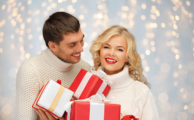 Image showing smiling man and woman with presents over lights