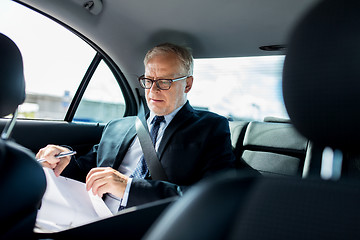 Image showing senior businessman with papers driving in car