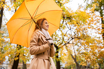 Image showing happy woman with umbrella walking in autumn park