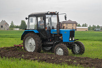 Image showing Tractor operator plows the site in rain
