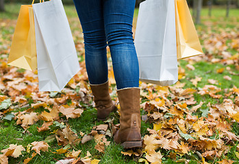 Image showing woman with shopping bags walking along autumn park