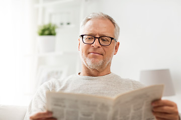 Image showing senior man in glasses reading newspaper at home