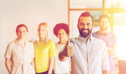 Image showing happy man showing thumbs up over team in office